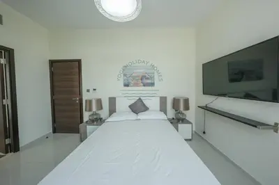 a white bedroom with a large bed and a flat screen tv at Spacious Private 4-Bedroom Villa for Families & Groups in Dubai