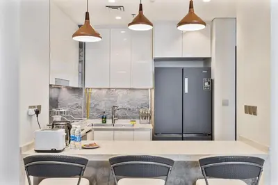 a kitchen with a counter with chairs and a refrigerator at Relaxing 2BR in Business Bay Mins to Burj Khalifa in Dubai