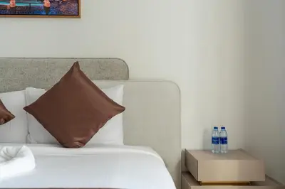 a bed with white sheets and pillows and a night stand with two water bottles at Samaya Holiday Homes - Lake City Stunning Suits Lake View - Next to Metro in Dubai