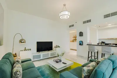 a living room with a blue couch and a tv at RH Luxe Vibes 2BR Al Habtoor City, Mesmerizing Canal View in Dubai