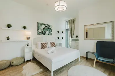 a bedroom with a white bed and a blue chair at RH Luxe Vibes 2BR Al Habtoor City, Mesmerizing Canal View in Dubai