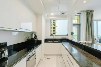 a kitchen with white cabinets and black counter tops at RH Luxe Vibes 2BR Al Habtoor City, Mesmerizing Canal View in Dubai