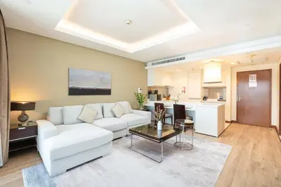 a living room with a white couch and a kitchen at PVH - Dubai Mall Access 1BR - Emaar Fashion Avenue in Dubai