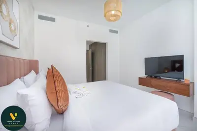 a bedroom with a white bed and a flat screen tv at Vogue Al Maktoum City, District One Residence, within a short drive from Downtown Burj Khalifa and Dubai Mall, Three Bedroom Apartment plus Kids Room with Large Balcony in Dubai