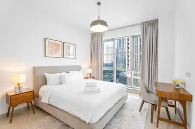 a bedroom with a bed and a desk and a window at Boema Apartments- Luxury with Burj Khalifa View in Dubai