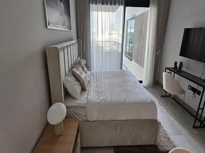a bedroom with a bed and a desk and a window at Beautiful Studio in Jumeirah Village Circle in Dubai