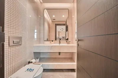 a bathroom with a sink and a toilet and a mirror at FAM Living Stylish 1BR in Nobles Tower Near Downtown in Dubai