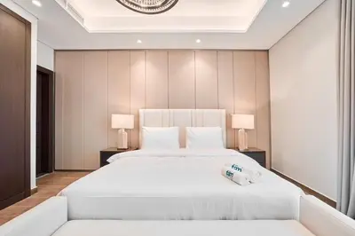 a bedroom with a large white bed with two lamps at FAM Living Stylish 1BR in Nobles Tower Near Downtown in Dubai