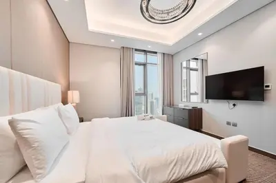 a bedroom with a large white bed and a flat screen tv at FAM Living Stylish 1BR in Nobles Tower Near Downtown in Dubai