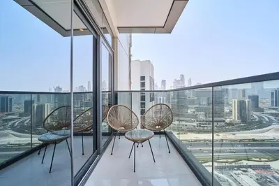 a balcony with three chairs and a view of the city at FAM Living Stylish 1BR in Nobles Tower Near Downtown in Dubai