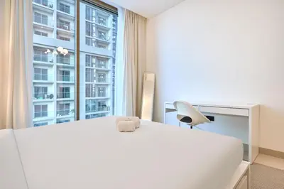 a bedroom with a white bed and a desk and a window at STAY BY LATINEM Luxury 2BR Holiday Home CVR B405 Near Burj Khalifa in Dubai
