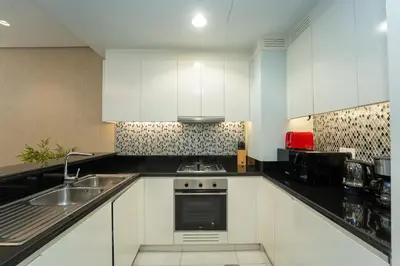 a kitchen with white cabinets and a sink at Paramount Hotel Midtown 2BR Apartment With Burj Khalifa View in Dubai