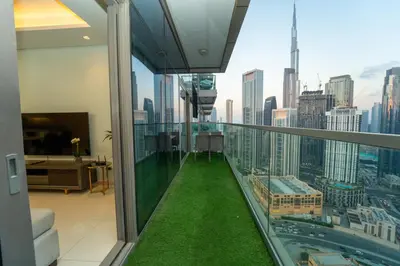 a balcony with green grass and a view of a city at Paramount Hotel Midtown 2BR Apartment With Burj Khalifa View in Dubai