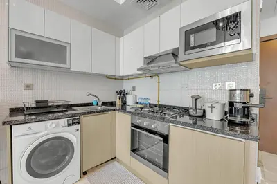 a kitchen with a washing machine and a washer at Waves - Vibrant Studio, Perfect For Couples in Dubai