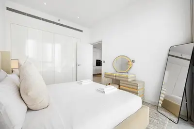 a white bedroom with a white bed and a mirror at The Pad luxury 1BR with full Canal View in Dubai