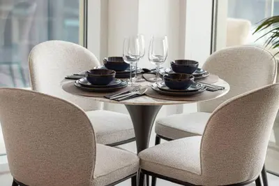 a table with four chairs with plates and wine glasses at Moon Stays - Canal View- 2BR Missoni Stay in Dubai
