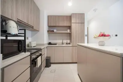 a kitchen with white cabinets and a bowl of fruit on the counter at Moon Stays - Canal View- 2BR Missoni Stay in Dubai