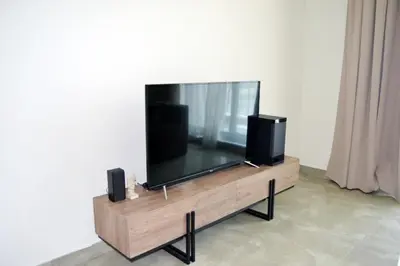 a flat screen tv on a wooden stand with speakers at Cozy spacious Modern 1 bedroom Apartment in Dubai