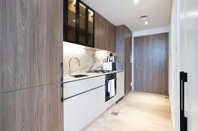 a kitchen with white counters and wooden cabinets at New Studio in JVC - Hamilton House at 5th floor in Dubai