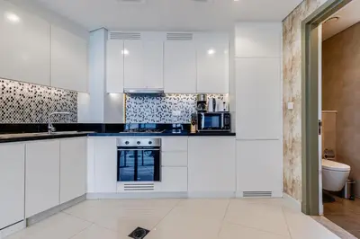 a kitchen with white cabinets and a sink at Paramount Midtown - 1 Bedroom Apartment - Allsopp & Allsopp in Dubai