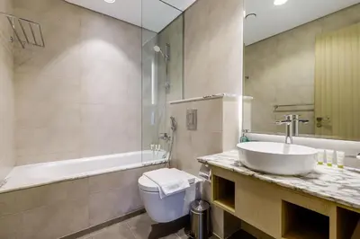 a bathroom with a sink and a tub and a toilet at Paramount Midtown - 1 Bedroom Apartment - Allsopp & Allsopp in Dubai