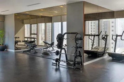 a gym with several treadmills and machines in a building at Paramount Midtown - 1 Bedroom Apartment - Allsopp & Allsopp in Dubai