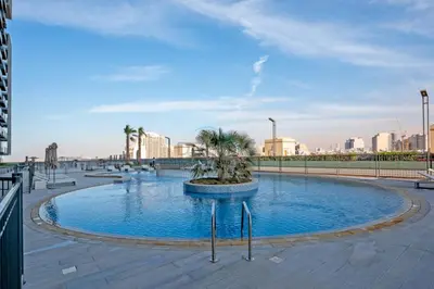 a small pool with palm trees in the middle of a city at Stay Near the Park with Easy Exit from JVC, Just Minutes to Dubai Marina and Palm Jumeirah - Bloom Towers A, JVC by Deluxe Holiday Homes in Dubai