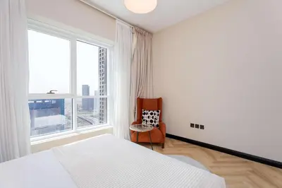 a bedroom with a bed and a chair and a window at Spacious 2BR Dubai Marina & City Views in Dubai
