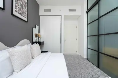 a bedroom with a white bed and a glass wall at Stylish 1BR Dubai Hills Walk to Park & Mall in Dubai
