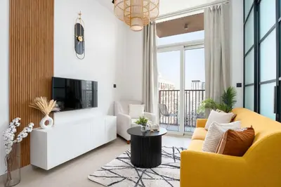 a living room with a yellow couch and a tv at Stylish 1BR Dubai Hills Walk to Park & Mall in Dubai