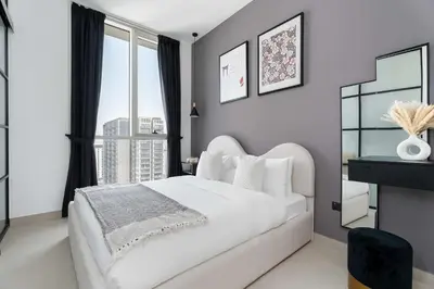 a bedroom with a white bed and a large window at Stylish 1BR Dubai Hills Walk to Park & Mall in Dubai