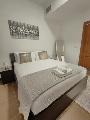 a bedroom with a large bed with white sheets at Bright & Spacious 2BR in JVT Community in Dubai