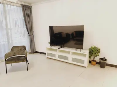 a living room with a television and a chair at Bright & Spacious 2BR in JVT Community in Dubai