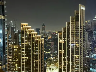 a view of a city at night with tall buildings at Balcony Bliss 1BR with City View Pool & Gym in Dubai