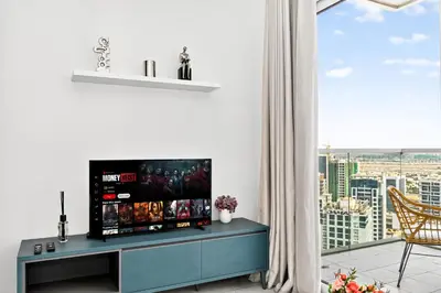 a living room with a flat screen tv on a blue cabinet at Skyline Views, Fully Equipped Studio with Balcony, Near Burj Khalifa in Dubai