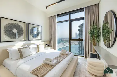 a white bedroom with a large bed and a large window at Luxurious 2BR with Sea and Burj View by BMS in Dubai