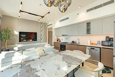a kitchen and living room with a table and chairs at Luxurious 2BR with Sea and Burj View by BMS in Dubai