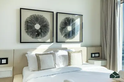 a bedroom with a bed with three pictures on the wall at Luxurious 2BR with Sea and Burj View by BMS in Dubai