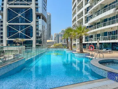 a large swimming pool with palm trees and buildings at Modern 1 Bed With Marina Views Near JBR Beach in Dubai