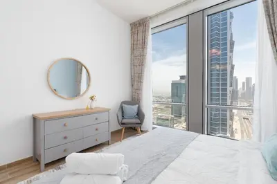 a bedroom with a bed and a window with a chair at Bellaviu Holiday Homes,1BR Elegant Stay, Noora Tower, Business Bay in Dubai