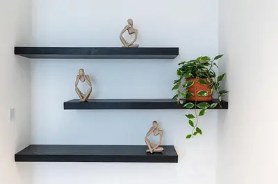 two woman figurines on black shelves with a plant at Bellaviu Holiday Homes,1BR Elegant Stay, Noora Tower, Business Bay in Dubai