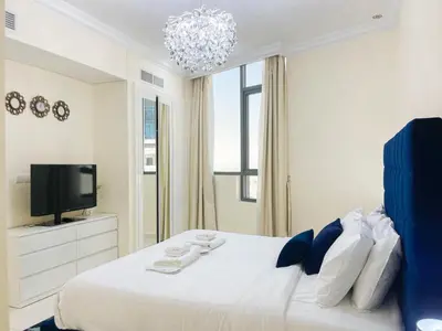a white bedroom with a large bed and a tv at 2 Bedroom Apt in Damac Capital Bay Tower A, Business Bay by Luxaura in Dubai