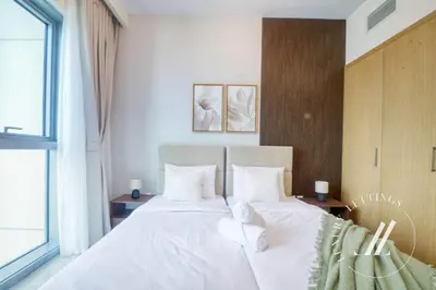 a bedroom with a bed with white sheets and pillows at Luxury 1BR Harbour Views Tower 2 Creek Harbour Dubai in Dubai