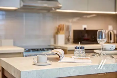 a kitchen counter with a book and a glass of wine at Luxury 1BR Harbour Views Tower 2 Creek Harbour Dubai in Dubai
