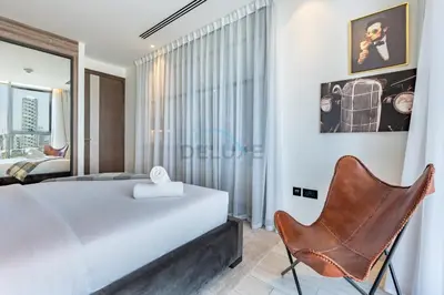 a bedroom with a white bed and a chair at Close to Dubai Miracle Garden, Dubai Autodrome, and Sports City, with JVT Community Park just steps away - The Ivy, Jumeirah Village Triangle by Deluxe Holiday Homes in Dubai
