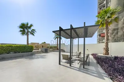 a patio with a table and chairs and palm trees at Close to Dubai Miracle Garden, Dubai Autodrome, and Sports City, with JVT Community Park just steps away - The Ivy, Jumeirah Village Triangle by Deluxe Holiday Homes in Dubai