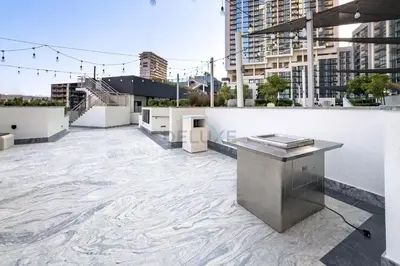 a rooftop with a table on top of a building at High-Floor 2BR with Skyline Views, Steps from a Park, Minutes Drive to Meydan Golf Club and Ras Al Khor Wildlife Sanctuary, Sobha Hartland The Crest Tower C, Sobha Hartland by Deluxe Holiday Homes in Dubai