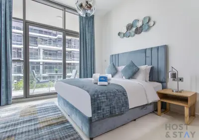 a bedroom with a bed and a large window at Cozy Studio in Orchid - Damac Hills Dubai in Dubai
