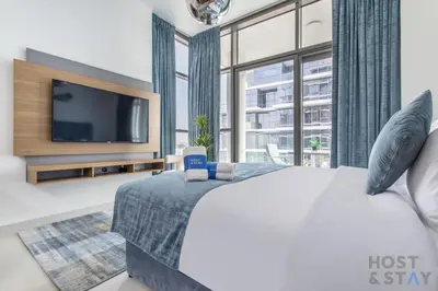 a bedroom with a bed and a large window at Cozy Studio in Orchid - Damac Hills Dubai in Dubai