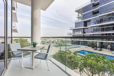 an apartment balcony with a table and chairs and a pool at Cozy Studio in Orchid - Damac Hills Dubai in Dubai